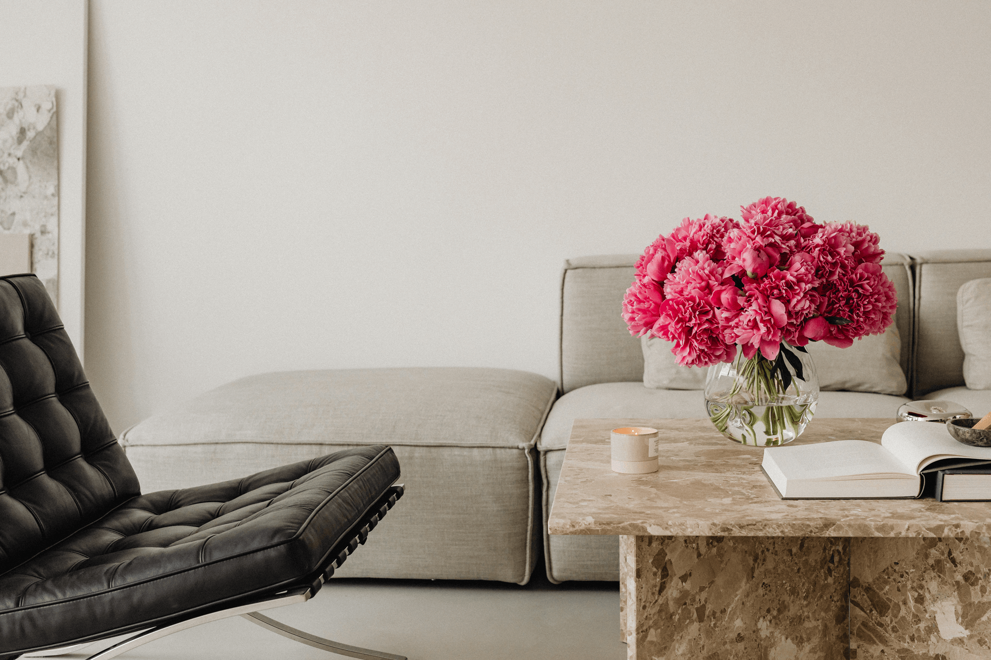 Living room with a gray sofa, black chair, and a table with pink flowers.