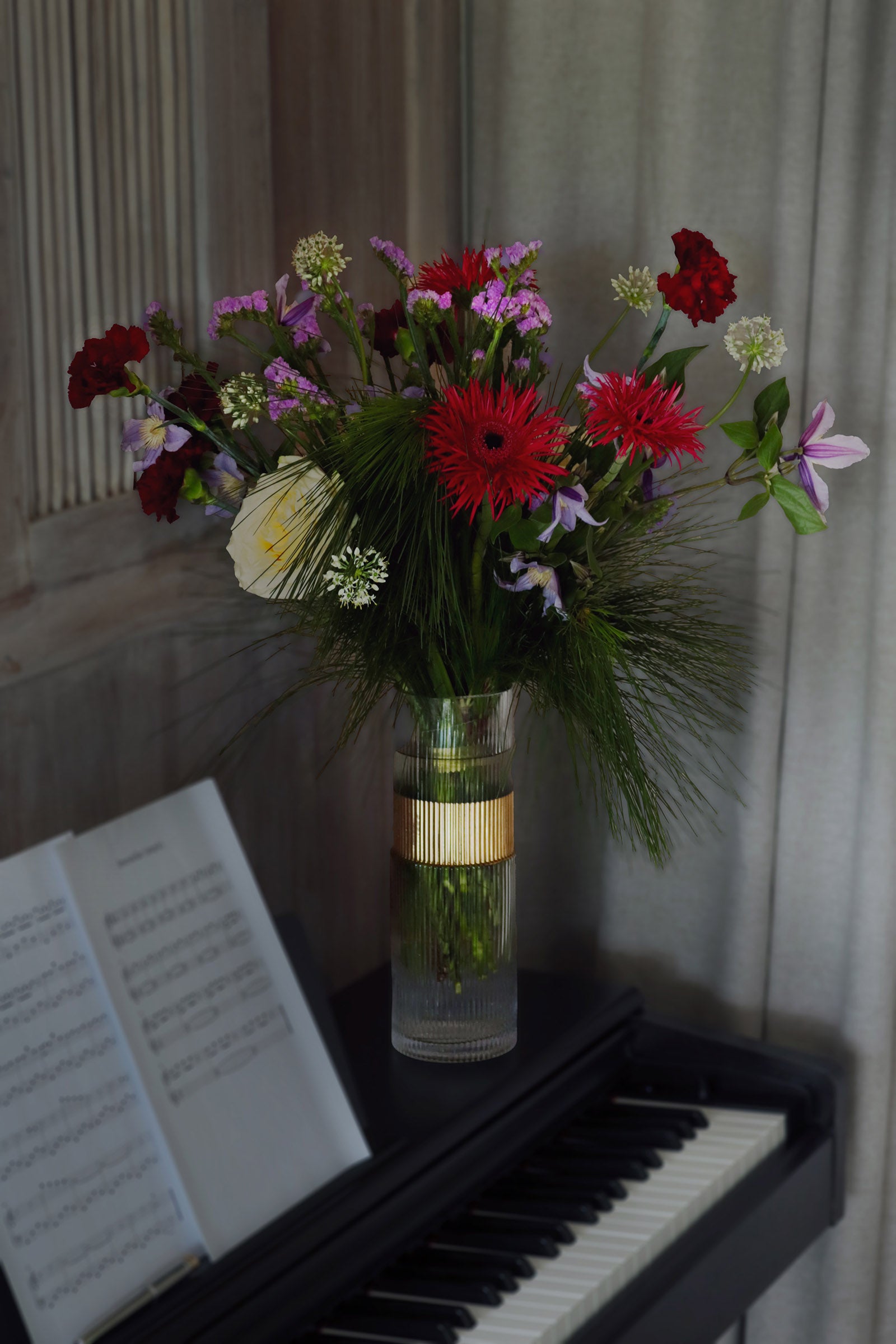 Vase of flowers on a piano with sheet music