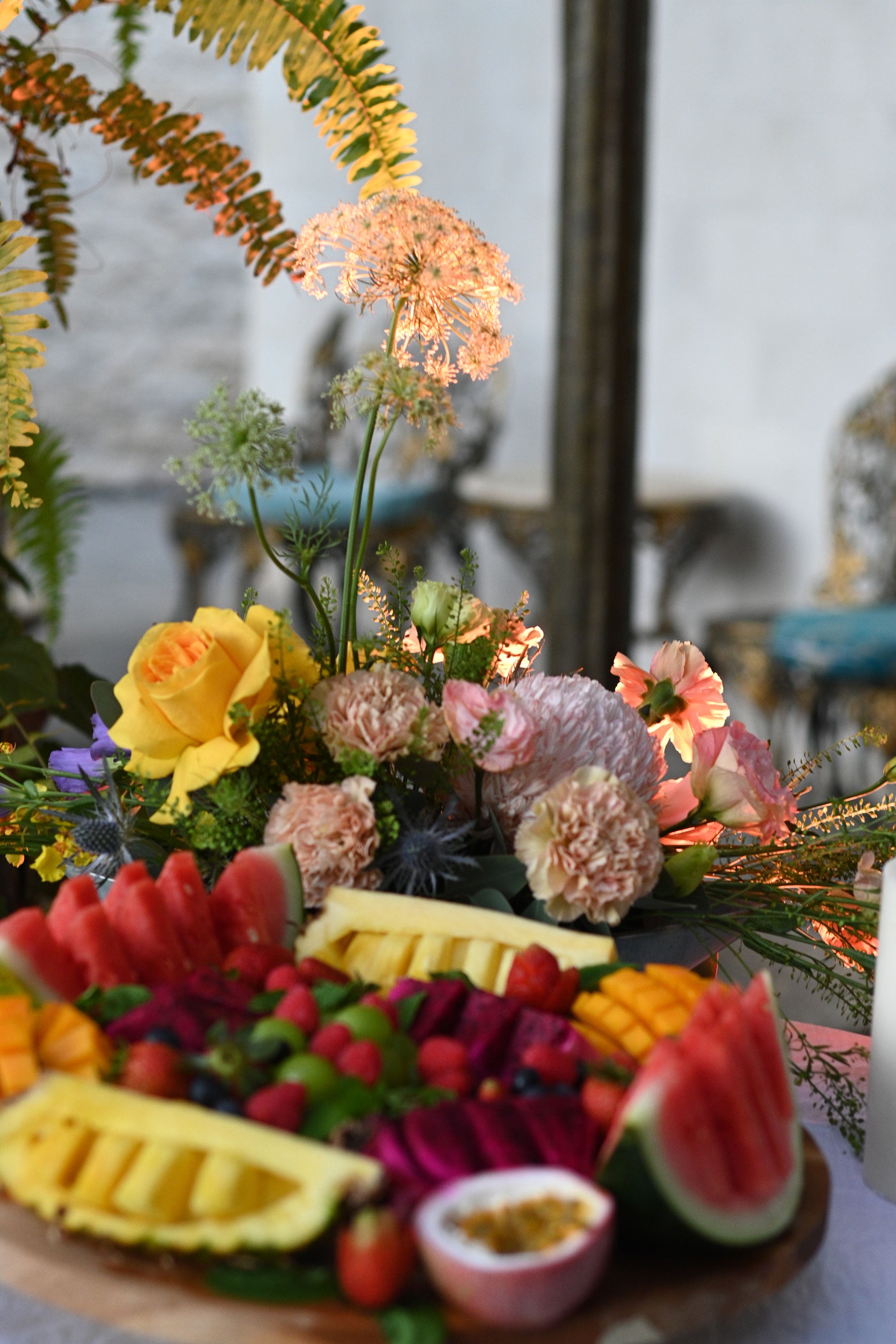 Decorative table setting with flowers, fruits, and a candle.